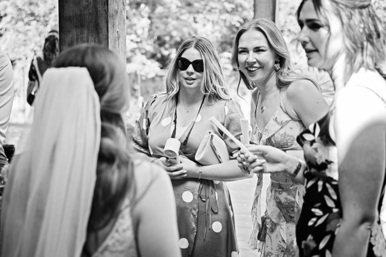 B&w photo of wedding guests smiling at the bride at a wedding.