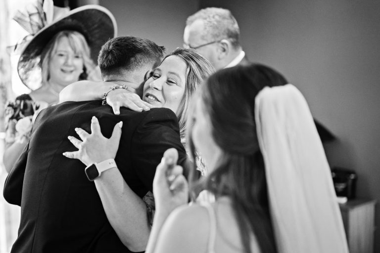 Natural, story telling photo of wedding guest hugging the groom.
