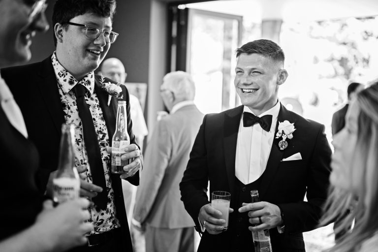 Groom naturally chatting to his wedding guests. B&W photo.
