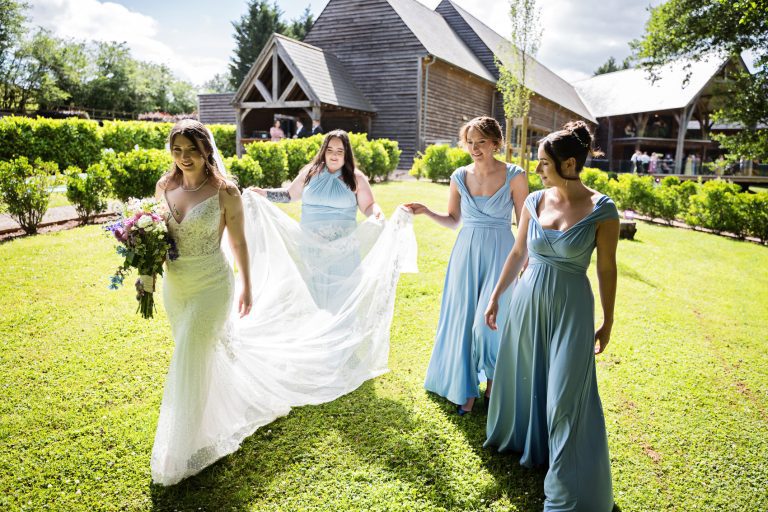 Team bride walking whilst holding the brides dress.