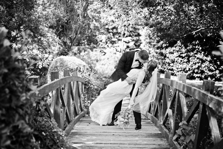Bride and groom do the "dip" on a bridge at The Mill Barns.