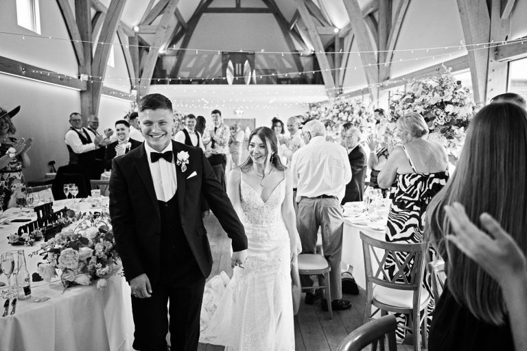 B&W candid photo of the bride and groom entering the wedding breakfast at The Mill Barns.