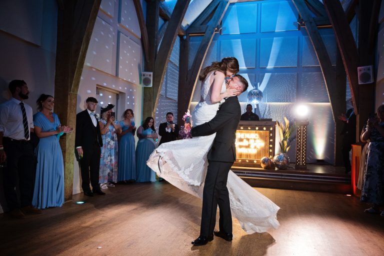 First dance photo of the groom picking up the bride (her dress is flowing through the air) at Mill Barns